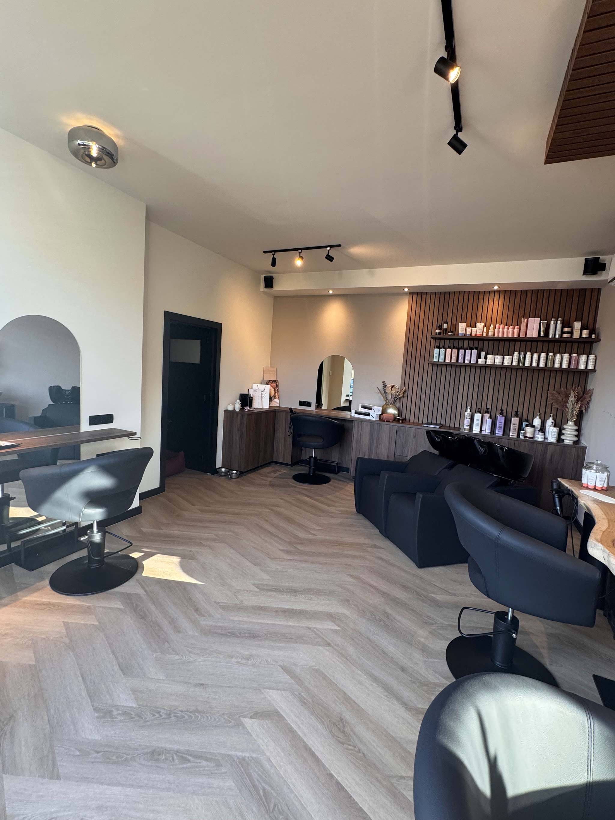 Het interieur van Steil Studio met visgraatvloer, zwarte stoelen en een wand met houten lamellen