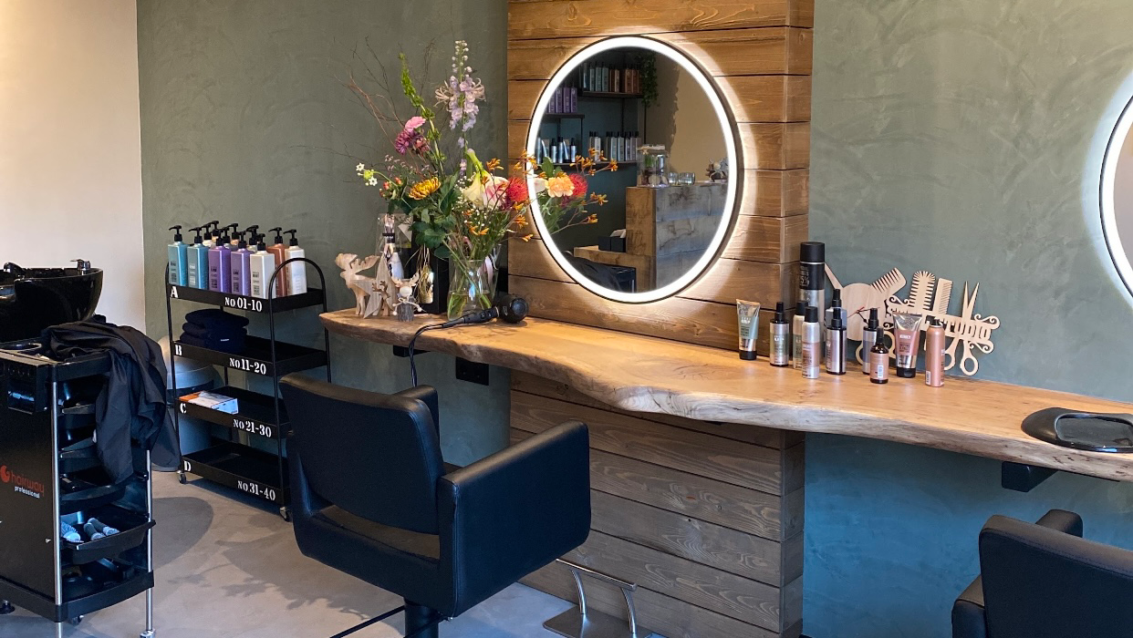 De studio: houten werkblad met ronde verlichte spiegel en bloemen